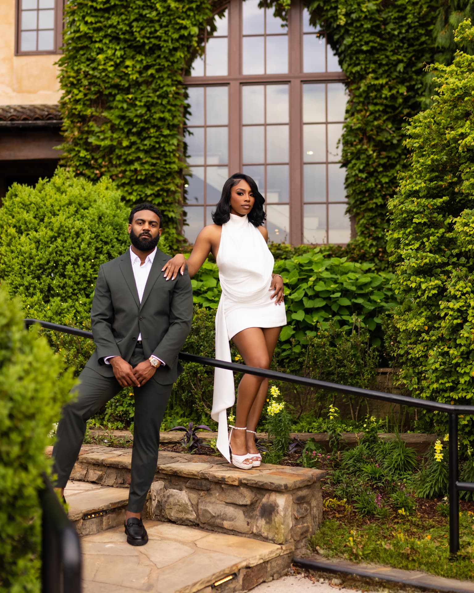 Couple posing on stone steps in front of an ivy-covered building