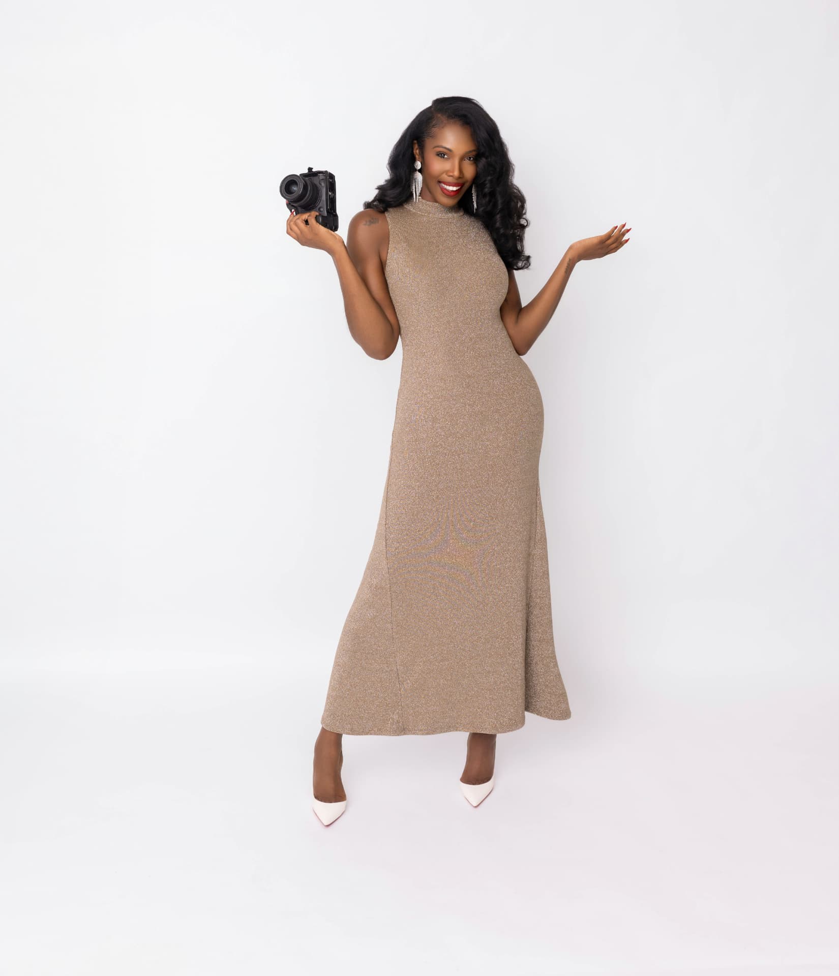 Jasmine “JLavii” Hutcherson smiling in a shimmering gold dress, holding her camera