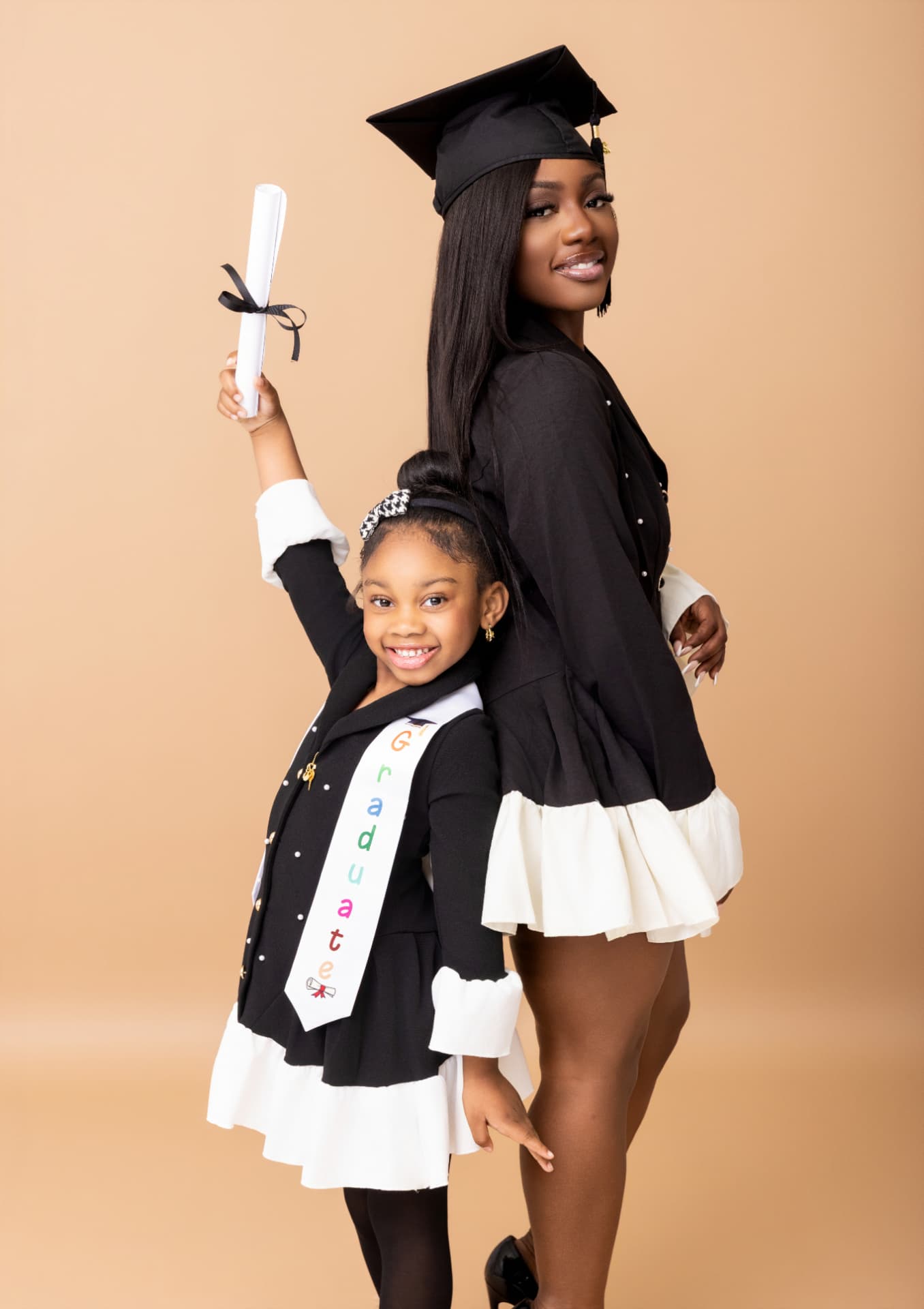 Graduate and young girl posing together with a rolled diploma