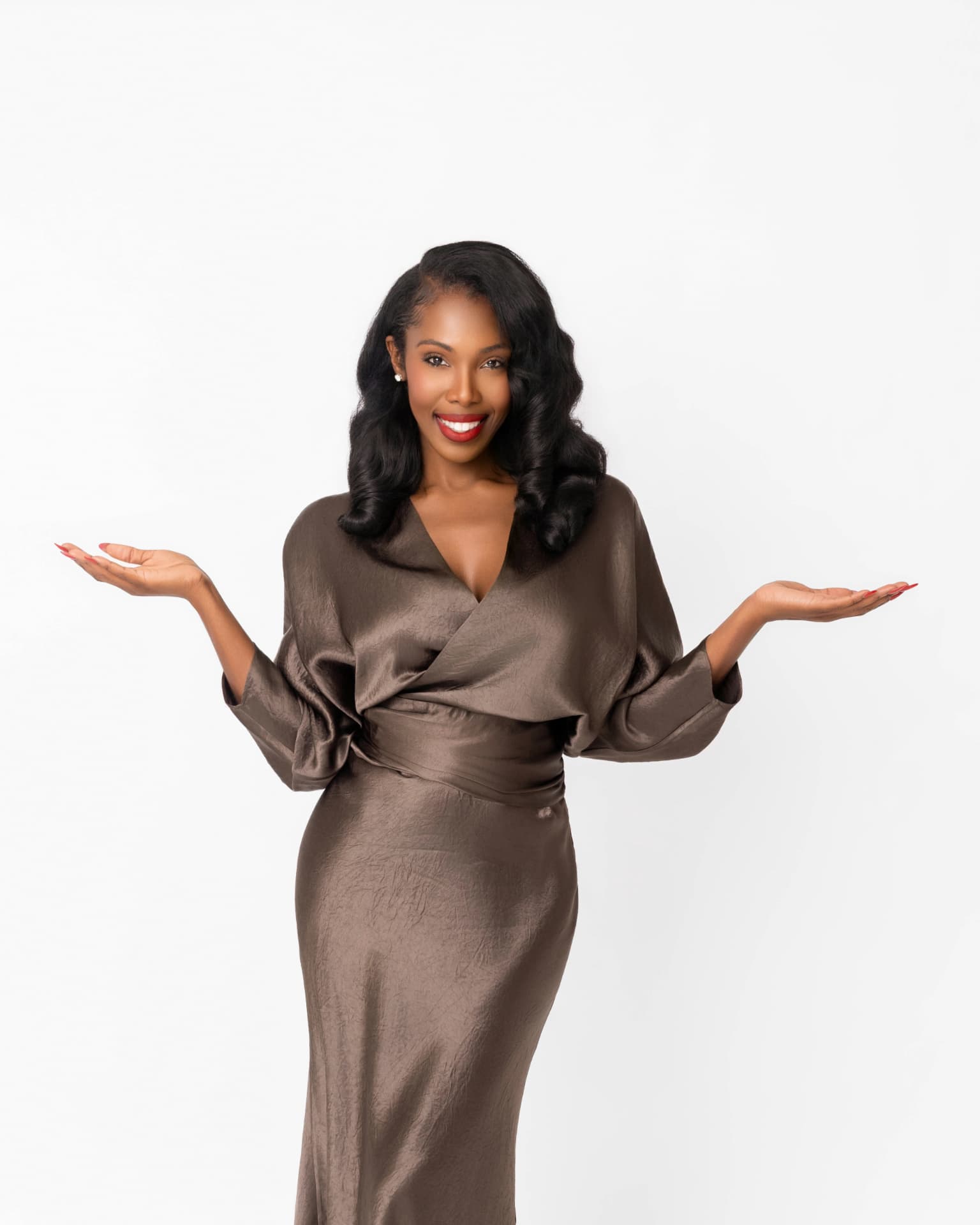 Jasmine smiling with open hands in a satin dress